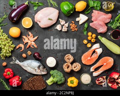 Mediterrane Ernährung Konzept mit Kopie Platz im Zentrum. Blick von oben auf die selektive Zutaten der mediterranen Diät auf dunklem Hintergrund. Flach. Stockfoto