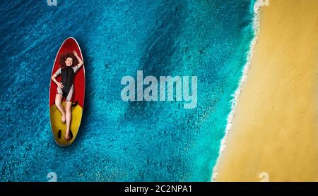 Nette weibliche sportman Windsurfer in Neoprenanzug liegt an Bord, Ansicht von oben Meer und Küste im Hintergrund Stockfoto