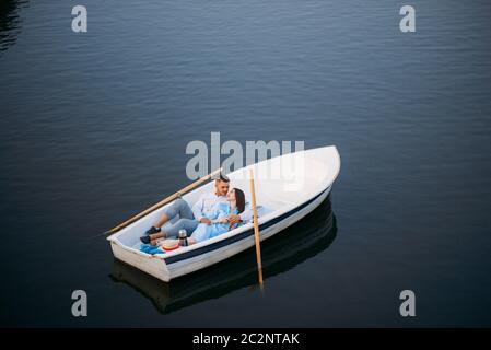 Liebespaar, das in einem Boot auf dem stillen See liegt, von oben gesehen. Romantische Treffen, Bootstour, Mann und Frau, die am See entlang spazieren Stockfoto