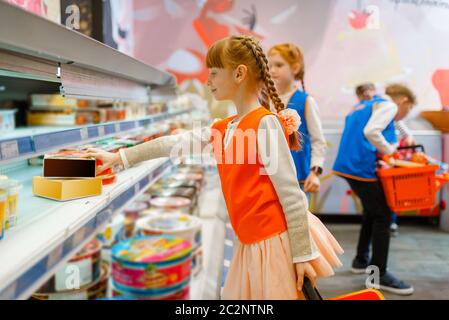 Kinder in Uniform spielende Verkäuferinnen, Spielzimmer. Kinder spielt Verkäufer an der Vitrine in imaginären Supermarkt, Verkäufer Beruf lernen Stockfoto