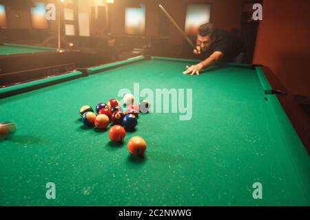 Spieler bricht eine Pyramide in Billard. Nachtleben. Billardzimmer im Hintergrund. Stockfoto