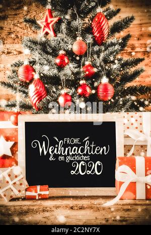 Deutsche Kalligraphie Frohe Weihnachten und ein Glueckliches 2020 bedeutet, frohe Weihnachten und einen guten Rutsch ins Jahr 2020. Hellen Weihnachtsbaum mit Geschenken, rote Kugel Orna Stockfoto