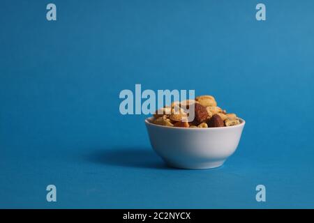 Nussmischung in weißer Schale isoliert auf blauem Hintergrund. Das Bild enthält den Kopierbereich Stockfoto