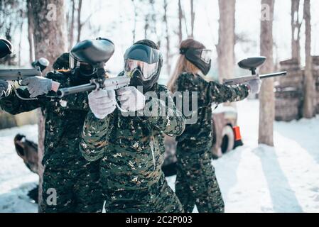 Paintball Spieler in Uniform und Masken wirft mit Marker Gewehren in den Händen nach dem Winter Wald Kampf. Extreme Sport Spiel Stockfoto