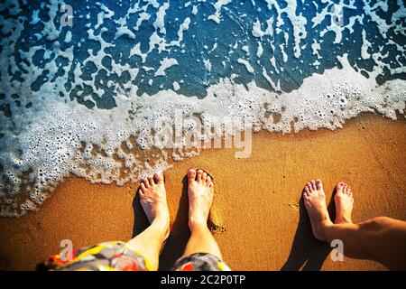 Männliche und weibliche Füße stehen auf dem Sandstrand Stockfoto