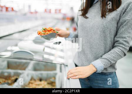 Frau nimmt ein Paket von gefrorenem Gemüse im Supermarkt, Familie einkaufen. Kundin kauft Produkte im Shop Stockfoto