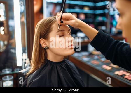 Make-up-Artist mit Pinsel, Frau in Make-up-Shop. Weibliche Client im Beauty Salon Stockfoto