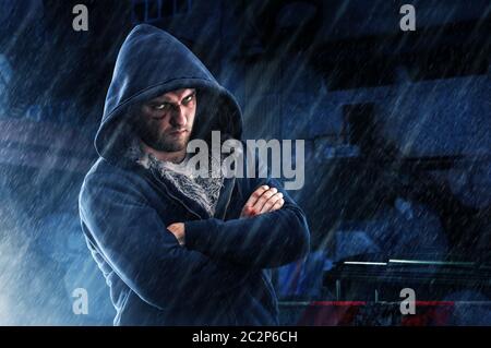 Verdächtigen Mann mit blauen Fleck und klopfte Fäuste in Hoodie über Nacht Straße im Regen. Kriminelle person, hooligan Fighter Stockfoto