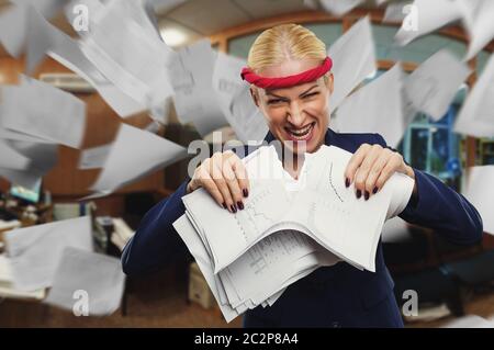 Wütende Geschäftsfrau zerreißt im Büro Papiere in Stücke Stockfoto