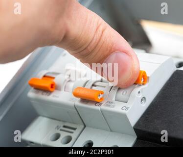 Hand eines Elektrikers Einschalten ein Sicherungskasten Stockfoto