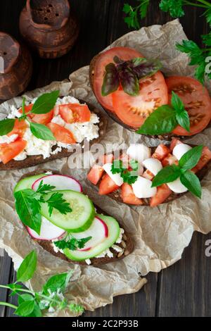 Italienische Bruschetta mit Tomaten, Parmesan, Gurke, Basilikum, Mozarella, Knoblauch und Olivenöl. Bruschetta flach legen Stockfoto