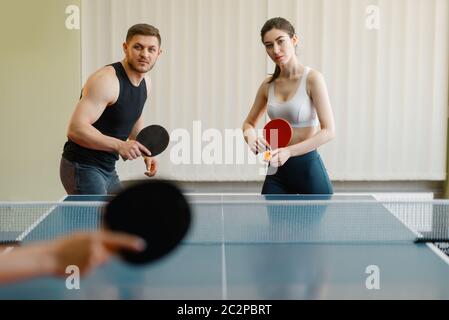 Freunde spielen Sport, Gruppe Tischtennis drinnen. Die Leute in Sportbekleidung hält Schläger und spielt Tischtennis im Fitnessstudio Stockfoto