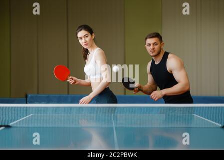 Eine Gruppe von Freunden, die Tischtennis spielen. Die Sportbekleidung hält Schläger und spielt Tischtennis im Fitnessstudio Stockfoto