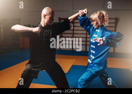 Männliche und weibliche Wushu-Kämpfer Übungen indoor, Martial-Arts. Sparring-Partner in Aktion Stockfoto