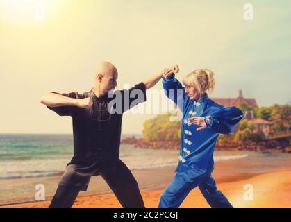 Männliche und weibliche Wushu-Kämpfer am Meer, Martial Arts training. Sparring-Partner in Aktion im freien Stockfoto