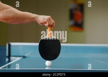 Männliche Person Hand mit Schläger und Tischtennis Ball auf dem Tisch, Training im Haus. Mann auf dem Training im Tischtennis-Club Stockfoto