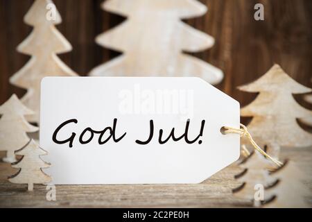 Label mit dem schwedischen Text Gott Aug bedeutet, frohe Weihnachten. Weiß Holz- Weihnachten Baum als Dekoration. Braun Holz- Hintergrund Stockfoto