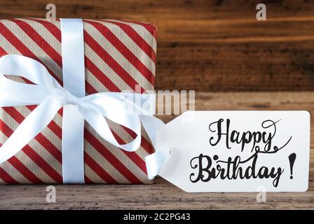 Ein Weihnachtsgeschenk mit Label mit englischen Kalligraphie Happy Birthday. Geschenkpapier mit Schleife Stockfoto