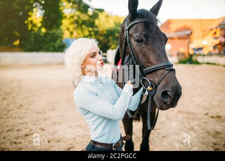 Reiterin umarmt ihr Pferd, Freundschaft, Reiten. Pferdesport, junge Frau und schöner Hengst, Nutztier Stockfoto