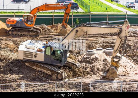 Zwei Bagger auf ausgegrabenen Boden während des Baus einer Straße in der Stadt Stockfoto