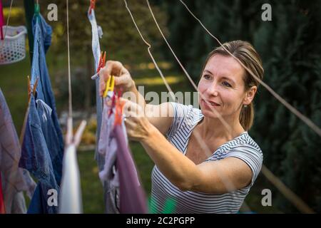 Junge Frau, Wäsche auf einem Seil in ihrem Garten, von ihrer Familie auf einer täglichen Grundlage Stockfoto