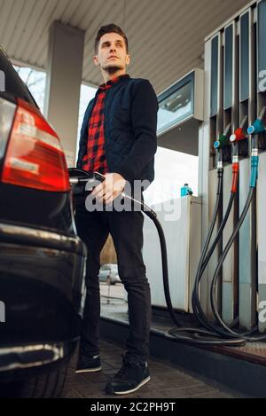 Mann mit Pistole Kraftstoff Fahrzeug auf Tankstelle, Ansicht von unten, Kraftstoff Füllung. Benzin tanken, Benzin oder Diesel tanken Service Stockfoto