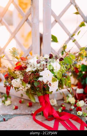 brautstrauß aus weißen und roten Rosen, kleinen Waldbeeren und roten Bändern Stockfoto