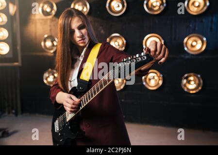 Weibliche Musiker in Anzug spielen auf E-Gitarre, Bühne mit Beleuchtung auf Hintergrund, retro style. Live musik Interpret, rock Gitarrist Stockfoto