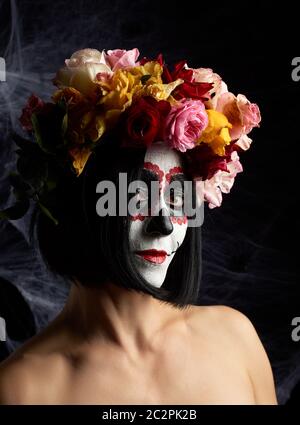 Mädchen mit traditionellen mexikanischen Tod Maske. Calavera Catrina. Sugar Skull Make-up. Mädchen in einem Kranz von Rosen auf einem Hintergrund von weißen Web gekleidet Stockfoto