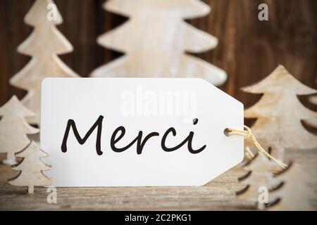 Etikett mit französischen Text Merci bedeutet. Vielen Dank. Weiß Holz- Weihnachten Baum als Dekoration. Braun Holz- Hintergrund Stockfoto