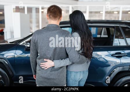 Paar, die neue Auto in Showroom, Rückansicht. Männliche und weibliche Kunden sieht Fahrzeug in Autohaus, Autoverkauf, Auto-Kauf Stockfoto