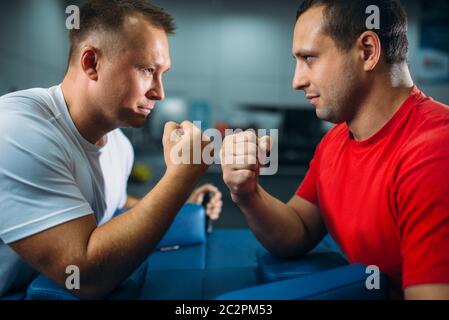 Zwei Arm Ringer kämpfen auf Ihren Händen am Tisch mit Stiften, der den Staub aus dem talkum in der Luft, wrestling Wettbewerb. Ringen Herausforderung, Power s Stockfoto