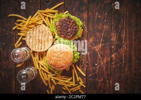 Zwei leckere gegrillte hausgemachte Burger mit Rindfleisch, Tomaten, Zwiebeln und Salat Stockfoto