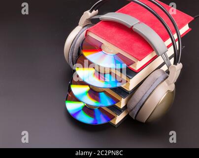 CD-Laufwerk ragt aus Haufen von roten Bücher mit Kopfhörern über Bücher Stockfoto