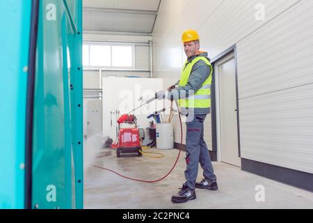 Arbeiter Reinigung einer Miete oder mobile Toilette mit Wasserschlauch Stockfoto