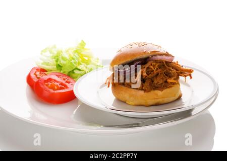 Schweinebraten in Hamburger Brötchen auf Teller mit frischem Salat. Stockfoto