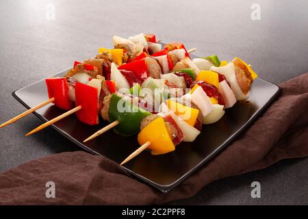 Hühnchen-Kebab. Rohes Fleisch und Gemüse auf Spieße, fertig zum Grillen auf schwarzem Hintergrund. Stockfoto