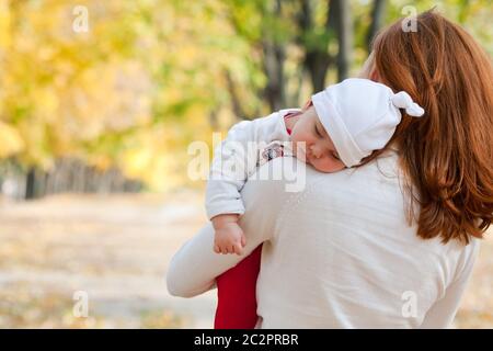 Schlafende Mädchen auf Mutters Schulter im Herbst park Stockfoto