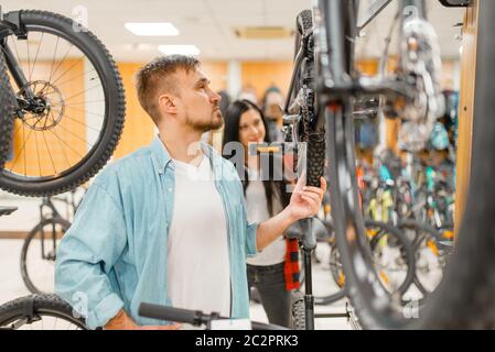 Mann überprüft Fahrrad-Scheibe Pausen, Einkaufen im Sportgeschäft. Sommer Saison extreme Lifestyle, aktive Freizeit-Shop, Kunden kaufen Zyklus, Paar wählen Stockfoto