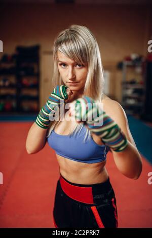 Weibliche kickboxer im Boxen Bandagen und Sportswear, üben Handstanze mit männlichen Personal Trainer in Pads, trainieren Sie im Fitnessraum. Frau Boxer auf Training, Stockfoto