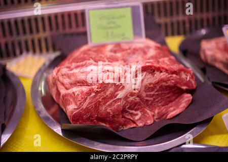 Rohes Kalbsfleisch in einer kalten Theke mit Preisschildern zum Verkauf in der Metzgerei angezeigt. Stockfoto
