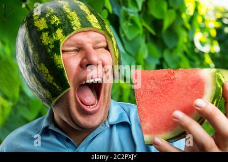 Bizarre Mann in eine Kappe aus einer Wassermelone essen im freien Stockfoto