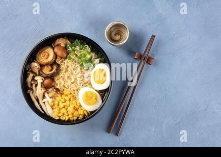 Ramen. Soba Nudeln mit gekochten Eiern, Shiitake-Pilze und Gemüse, von oben mit Essstäbchen, Sake und ein Ort f geschossen Stockfoto