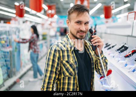 Mann mit elektrischen Rasierapparat, Paar im Supermarkt. Männliche und weibliche Kunden auf Familie einkaufen. Mann und Frau Einkauf von Gütern für das Haus Stockfoto