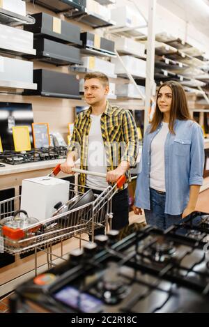 Junges Paar hält elektrischen Mixer in Elektronik-Shop. Mann und Frau kaufen elektrische Haushaltsgeräte auf dem Markt Stockfoto