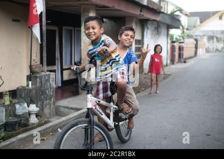 Mataram, Lombok, Indonesien - 21. August 2017: Einheimische Kinder fahren auf der Straße von Mataram, Indonesien, Fahrräder. Stockfoto