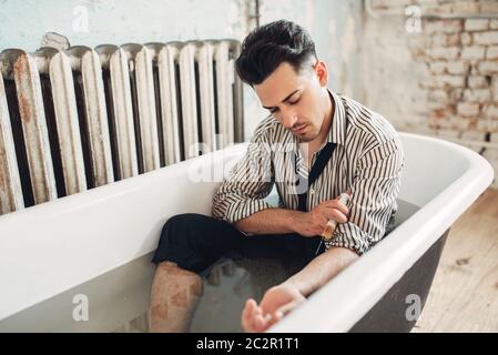 Unternehmer Bankrott will sich von einer Überdosis Drogen, Selbstmord Mann in der Badewanne sitzen zu sterben und gibt sich selbst eine Spritze Injizieren. Problem im Geschäft, Str Stockfoto