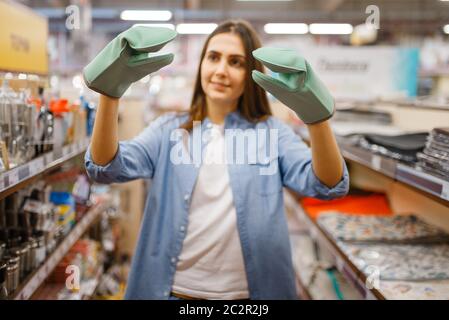 Junge Frau in hitzebeständigen Handschuhen, Haushaltswaren zu speichern. Weibliche Person Kauf von Wohnwaren auf dem Markt, Dame in Küchengeschirr Versorgung Shop Stockfoto
