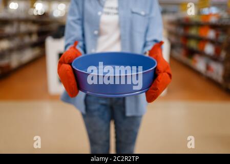 Frau in Handschuhen hält Schüssel, Haushaltswaren zu speichern. Weibliche Person Kauf von Wohnwaren auf dem Markt, Dame in Küchengeschirr Versorgung Shop Stockfoto