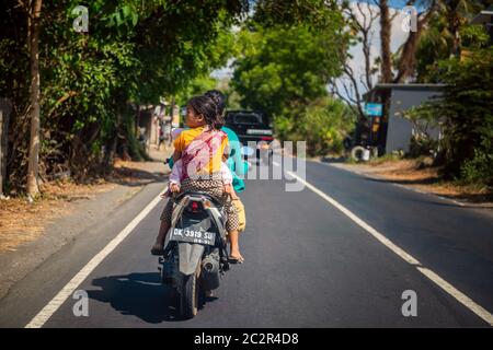 BALI, INDONESIEN - 01. Dezember 2019: Traditionelles balinesisches Stammdorf. Autos und Motorräder fahren auf der Straße in Bali, Indonesien Stockfoto